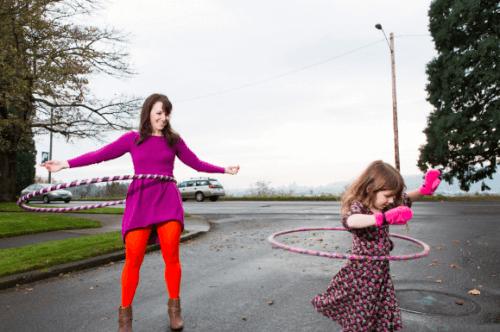Parent and child playing with Big and Little Hoops together outdoors.